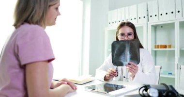 Parlak ve sağlıklı bir tıbbi ofis ortamında bir doktor, hastanın röntgen sonuçlarını titizlikle gözden geçirir.