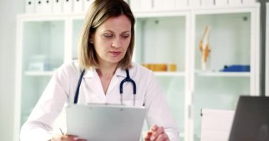 Kendini adamış bir sağlık uzmanı bugün klinik bir ortamda tıbbi kayıtları iyice analiz ediyor.