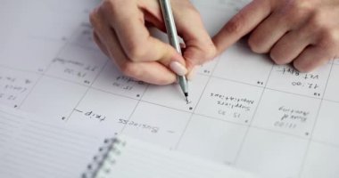 Günlük programlarını ve randevularını etkin bir şekilde yönetmek için bir takvime özenle yazı yazan bir kişi