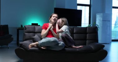 Anne ve kızı yan yana oturur ve sıcak gece sahnesinde canlı etkileşimlerini kulaklarına fısıldarlar.