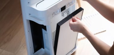 Bir kadın hava iyonizatöründen filtreyi çıkartıyor, yakın plan. Ev aletleri, hava arındırma, havalandırma, ekipman.