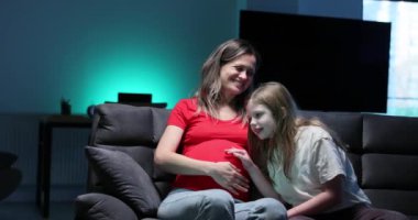 Hamile bir anne ve sevgili kızı arasında paylaşılan ve derin bir sevgi ve bağ gösteren yürek ısıtan bir an.