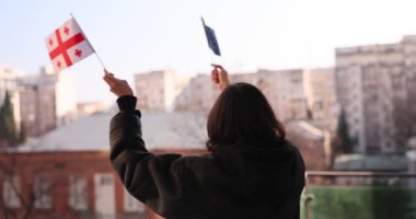 Hem Gürcistan hem de Avrupa Birliği bayraklarını tutkuyla sallayan bir kişi, umudu ve birlik fikrini temsil ediyor