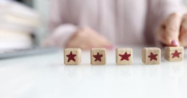 Yetenekli bir el parlak yıldız sembolleriyle renkli ahşap bloklar oluşturur, değerlendirme ve yaratıcılığı temsil eder.