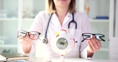 Bir göz bakımı uzmanı, insan gözünün detaylı modelinin yanında çeşitli türde bardaklar sunuyor.