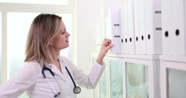 Bir doktor hasta dosyalarını özenle inceliyor. Sağlık ve mesleki ofis ortamında.