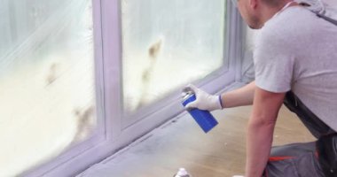 Yetenekli bir profesyonel titizlikle pencereleri spreyle temizler, modern, düzenli bir iç mekan sergiler.