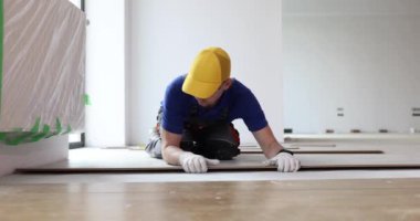 Çağdaş bir odada yerleri ustalıkla döşeyen profesyonel bir işçi, beceri ve ilgi sergiliyor..