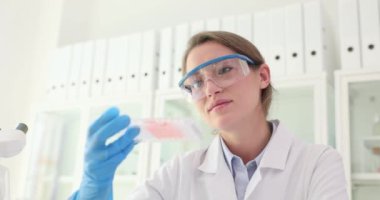 Kadın araştırmacı örneklerdeki değişiklikleri dikkatle gözlemliyor. Profesyonel bilim adamı, uygulamalı kimyasallarla olan etkileşimi analiz eder.