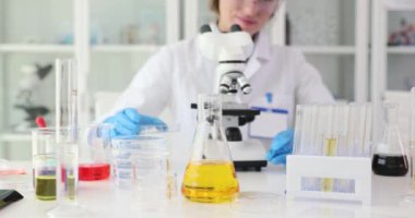 Nitelikli kadın araştırmacı mikroskop ayarlarını ayarlar. Bilimadamı, laboratuvar ekipmanlarını ayırıcı maddeyi düzgün bir şekilde analiz etmeye hazırlanıyor.