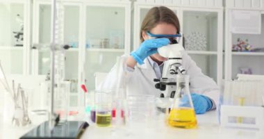 Kadın laboratuvar teknisyeni mikroskop altında örnekler üzerinde çalışıyor. Nitelikli laboratuar asistanı mikroskobik yapıları iyice yavaş çekimde analiz eder.