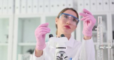 Kadın laboratuvar asistanı gözle görülür farklılıkları belirlemek için örnekleri karşılaştırır. Laboratuar teknisyeni cam slaytlar üzerinde yavaş çekim örnekleri inceliyor.