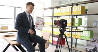 İş adamı ofiste kameranın önünde istatistiksel verileri sunar. Adam, finansal performans ve iş büyümesini özetleyen video konferansını kaydetti