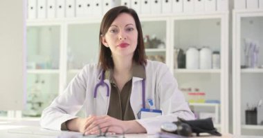 Kadın doktor hastanede işyerinde otururken başını sallayarak rızasını bildiriyor. Steteskoplu kadın doktor randevudaki hastayı dinliyor.