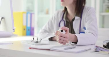 Kadın doktor hastanede iş yerinde otururken stres topu sıkar. Steteskoplu kadın doktorların iş sırasında gerginliği atması zaman alır.