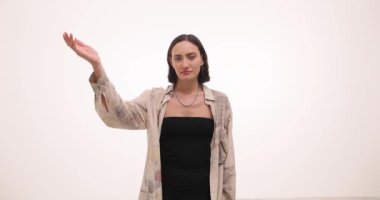 Genç bir kadın utancını ifade etmek için elleriyle kafasına dokunur. Gümüş kolyeli esmer kadın garip bir duruma tanıklık ederek fotoepalm hareketi yapıyor.