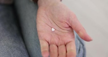 Kadının elinde avuç içinde kalp şeklinde küçük haplar var. Hanımefendinin elinde kalp sağlığını iyileştiren ve genel sağlık durumunu iyileştiren bir takviye var.