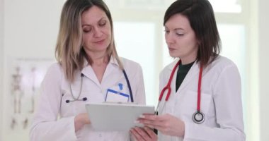 Asistanı hasta test sonuçlarını panoda klinikteki kadın doktora gösteriyor. Sıhhiye meslektaşları tedavi planını sağlık kayıtlarını okuyarak tartıştılar