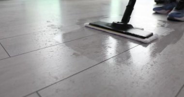 Temizlikçi dairede ıslak paspas temizleme malzemesi itiyor. İşçi, modern ev aletleriyle zeminden toprak ve tozu temizliyor.