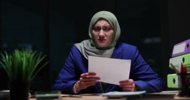 Tesettürlü kadın yönetici şirket ofisinde geç saatlere kadar çalışan mektupları okur ve yırtar. Arap kadın işçi aşırı çalışma öfkesini dile getiriyor