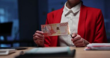 Kadın çakmağı yakıyor ve ruble banknotunun köşesine küçük bir alev getiriyor. Parlak ceketli bir kadın nefret edilen ruble paralarını yakmak için çakmak kullanır. Yavaş çekim