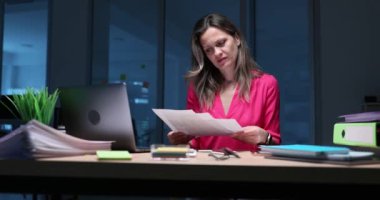 Sarışın kadın yöneticinin mali raporunda tutarsızlıklar var. Kırmızı elbiseli bir ofis çalışanı titizlikle evrak yığınını inceliyor. Yavaş çekim