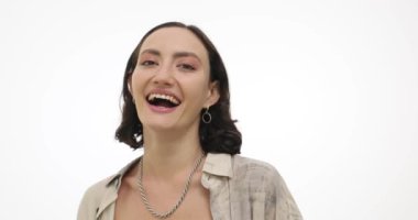 Gümüş kolyeli genç bir kadın neşe saçan mutluluğa gülüyor. Neşeli esmer kadın anekdota tepki veren elleriyle boynuna dokunuyor.