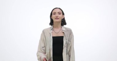 Genç bayan, elini beyazlara karşı göğsüne koyduğu için içten şükranlarını sunuyor. Gülümseyen esmer kadın selamları takdiri yansıtıyor.