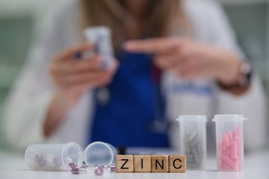 Bir sağlık uzmanı renkli konteynırlarla dolu bir eczanede farklı çinko takviyeleri sınıflandırıyor.
