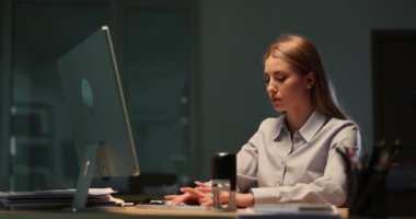 İş kadını bilgisayarda çalışırken, erkek iş arkadaşı iş belgelerini getiriyor. Stresli kadın çalışan, gece ofisinde yavaş çekimde belgeyi dağıtıyor.