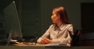 Hüsrana uğramış iş kadını gece ofisindeki pencerenin arkasındaki yıldırıma bakıyor. Sarışın işçi fırtınalı havada iş yerinde geç saatlere kadar kalır.