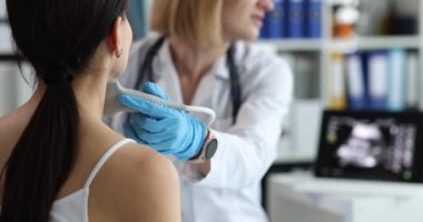 Kadın doktor kadın hastanın boynuna ultrason uygular. Steril eldivenli kadın doktor tiroid sağlığı incelemesi yapıyor.