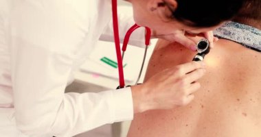 Bir sağlık uzmanı, klinik ziyareti sırasında bir hastaya kapsamlı bir cilt muayenesi yapmaktadır.