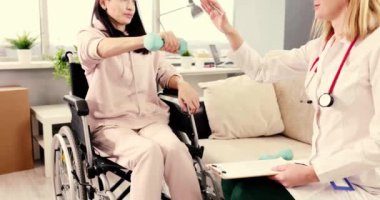 Terapist, tekerlekli sandalye kullanan bir hastaya ağırlıklar içeren fizik tedavi egzersizleri konusunda uzmanca yardımcı olur.