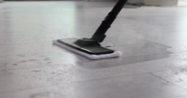 Profesyonel temizlikçi döşemeleri temizlemek için buhar paspası kullanır. Ev hanımı kiri ve kiri temizlemek için buharlı süpürgeyi ileri geri hareket ettirir. Yavaş çekim