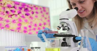 Kadın bilim adamı laboratuvarda mikroskop altında numuneleri inceliyor. Profesyonel araştırmacı küçük numune yapılarını dikkatle inceliyor. Yavaş çekim