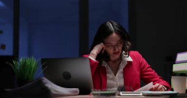 Yorgun iş kadını gece geç saatlerde belgeleri analiz eder. Bitkin esmer ofis çalışanı raporları incelemeyi bitirmeye çalışıyor. Yavaş çekim