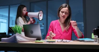 Liseli kız, çalışan annenin dikkatini dağıtan megafona rastgele cümleler söylüyor. Sinirli iş kadını kafasını tuttu ve yüksek sesle bağırdı. Yavaş çekim