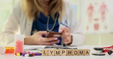 Sözcük lenfoması ve tıbbi uzmanlar akıllı telefondan detayları inceliyor. Kadın doktor hastanede dijital sağlık bilgilerine yoğunlaşıyor