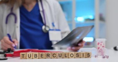 Tahta blokların tüberkülozu ve klinikte göğüs radyografisini analiz eden kadın doktor. Doktor iş yerindeki hastanın röntgen görüntülerini kontrol ediyor.