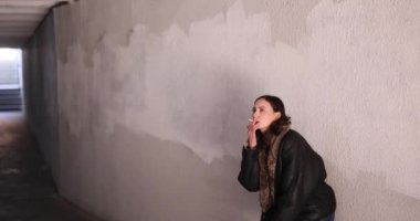 Düşünceli kadın sigara içiyor beton altgeçitte çömelmiş halde. Esmer kadın şehir yalnızlığını ve dışarıdaki yıkıcı bağımlılığı somutlaştırıyor.