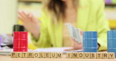 Oyuncak varillerinin yanındaki küplerde paralı iş kadınına karşı kullanılan ifade Petrol Endüstrisi. Kadın girişimci, iş ortağıyla işbirliğini onaylayan damgayı vurdu