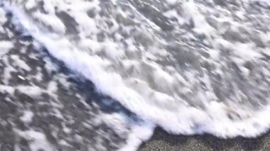 Köpüklü okyanus dalgaları, kumla yazılan kelime savaşını yıkıyor. Temiz su tabelayı kaldırır ve yazın kumlu sahilde huzurlu bir atmosfer yaratır.