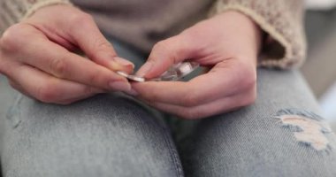 Kadın elleri koltukta otururken su toplamaktan ilaç alıyor. Kadın, reçeteli ilaçlarla belirtileri ortadan kaldırmaya çalışırken acı çekiyor.