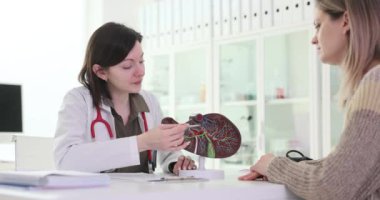 Kadın doktor hastaya hastalığı açıklayan karaciğer modelini gösteriyor. Kadın sıhhiyeci, hastane ofisinde ağır çekimde tehlikeli bir hastalık olduğunu bildirdi.