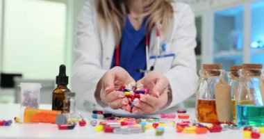 Kadın doktor masasından çok renkli kapsüller döker. Doktor hastane randevusu sırasında aşırı ilaç yazar.