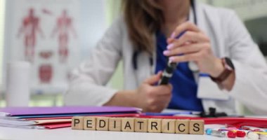 Tahta bloklardan oluşan bir pediatri ve klinikte otoskop ayarlayan bir doktor. Modern hastane ağır çekimde çocuklar için tıbbi hizmet