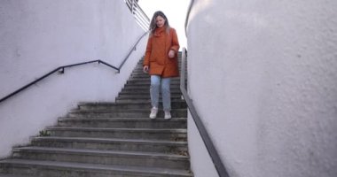 Kışlık ceketli sarışın kadın sokak merdivenlerinden aşağı koşuyor. Bayan sabah yeraltı geçidinde acele eder ve ağır çekimde iş yerine zamanında varmaya kararlıdır.