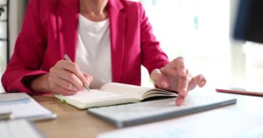Son derece odaklanmış ve kendini işine adamış bir iş kadını modern ofis ortamında çalışırken özenle not alıyor.