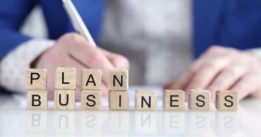 Yetenekli bir profesyonel, PLAN ve BÜYÜK etiketli ahşap bloklar kullanarak bir iş planı geliştiriyor.